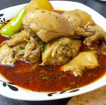 A bowl of Lahori Aloo Chicken Shorba, showcasing tender chicken, potatoes, and aromatic spices.